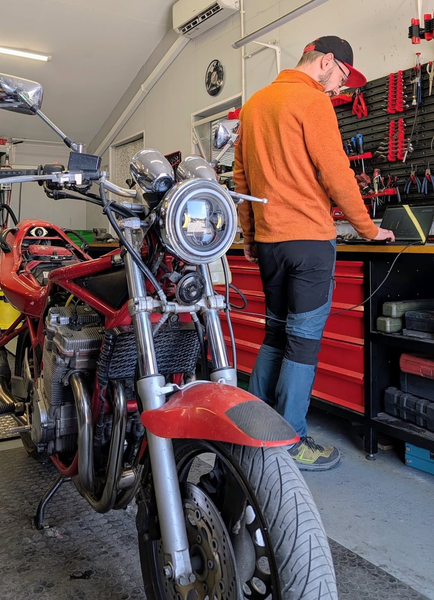 Karol przy stanowisku diagnostycznym, obok motocykl na podnośniku