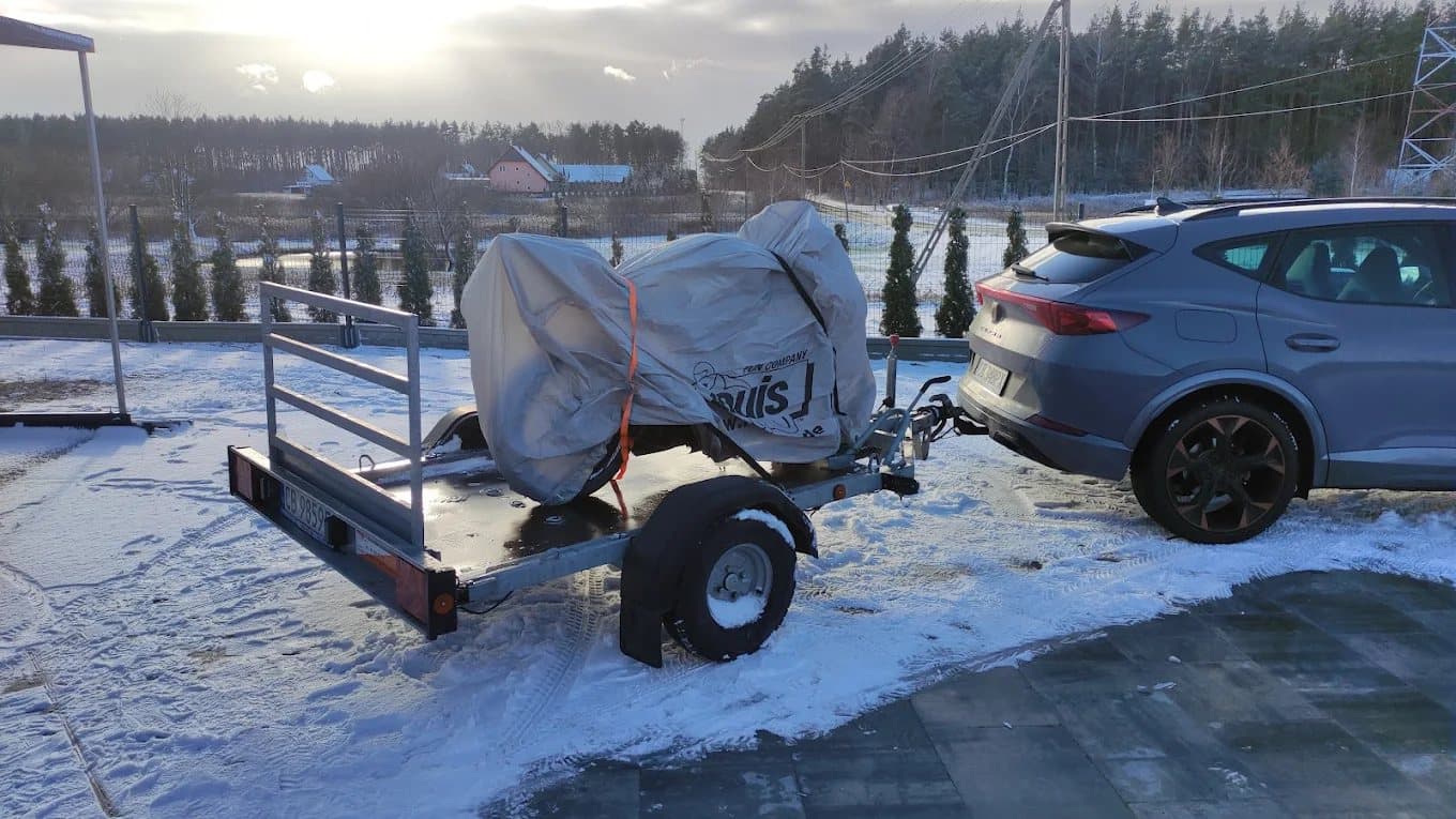 Motocykl pod pokrowcem na przyczepie, zimą